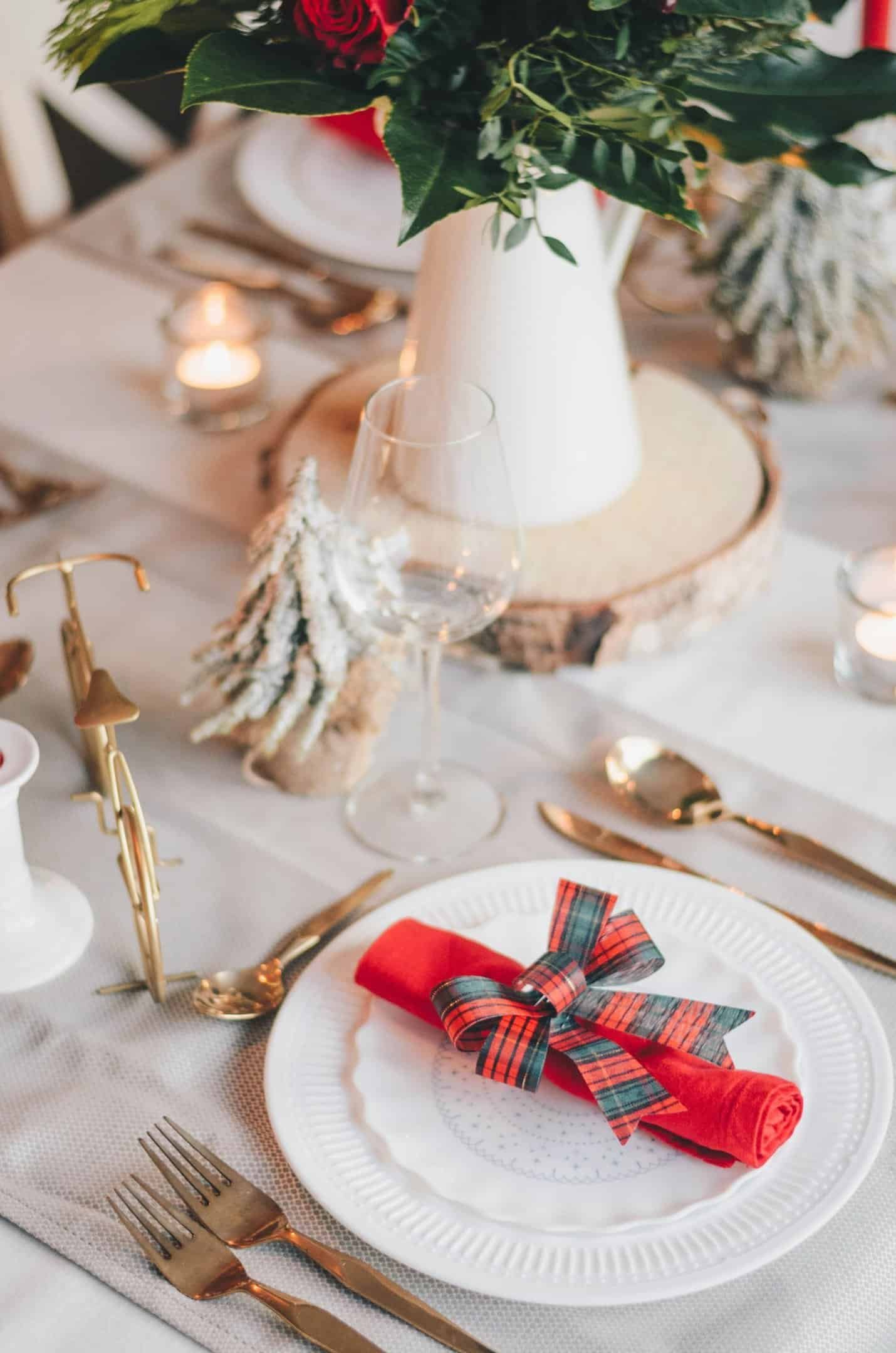 a table setting with a red napkin and a vase with flowers